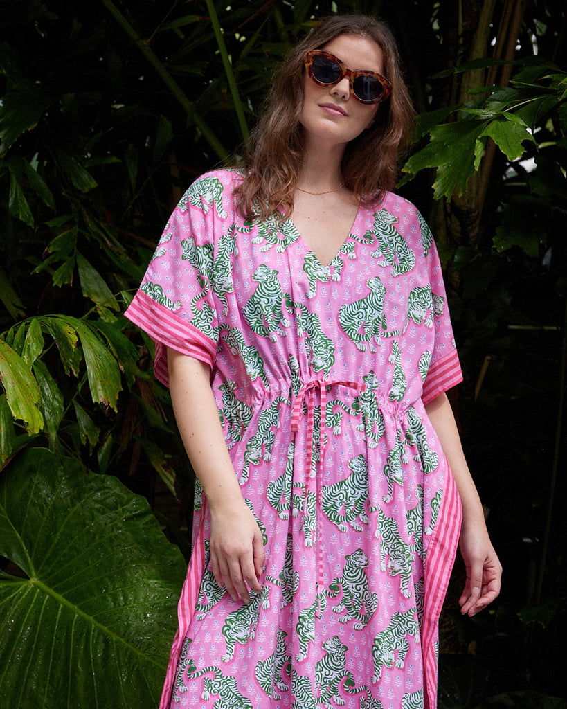 Close up photo of a woman wearing a bold pink and green tiger print long cover up