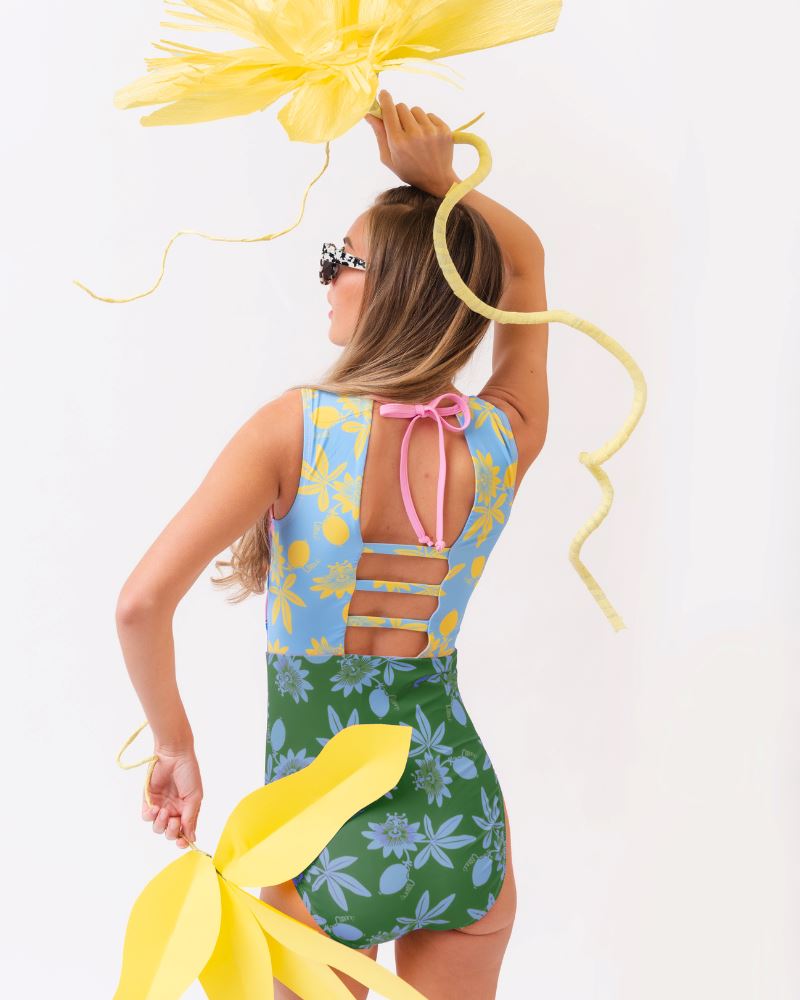 Photo of a woman wearing a multi-colored floral one-piece swimsuit- back angle