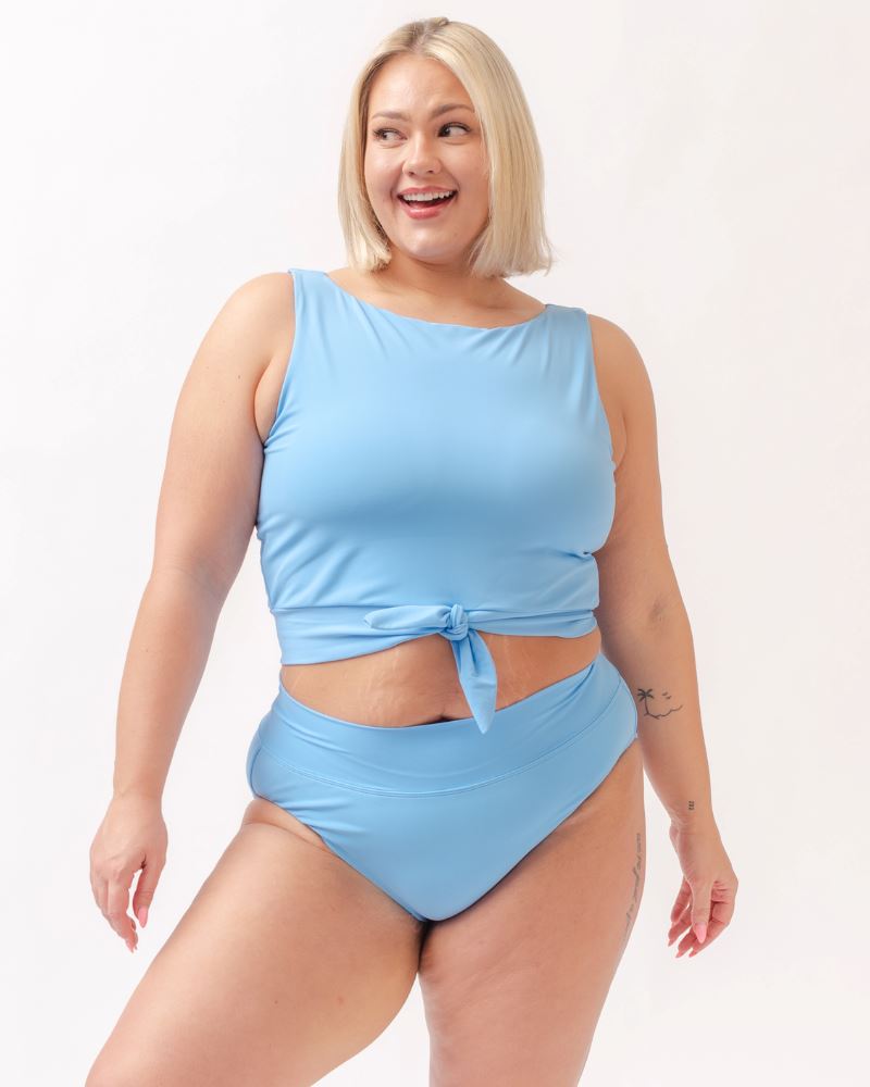 Photo of a woman wearing a light periwinkle blue knotted swim crop top and a light periwinkle blue classic swim bottom