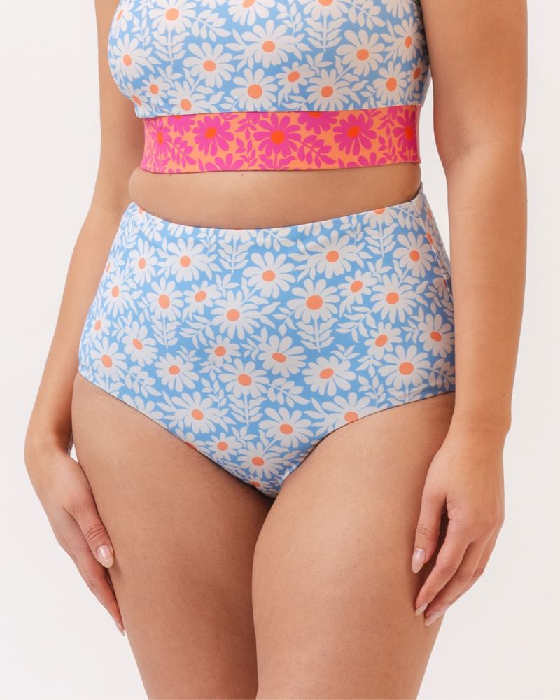 Close up photo of a woman wearing a blue and pink floral cropped swim top with blue floral high waist reversible swim bottoms