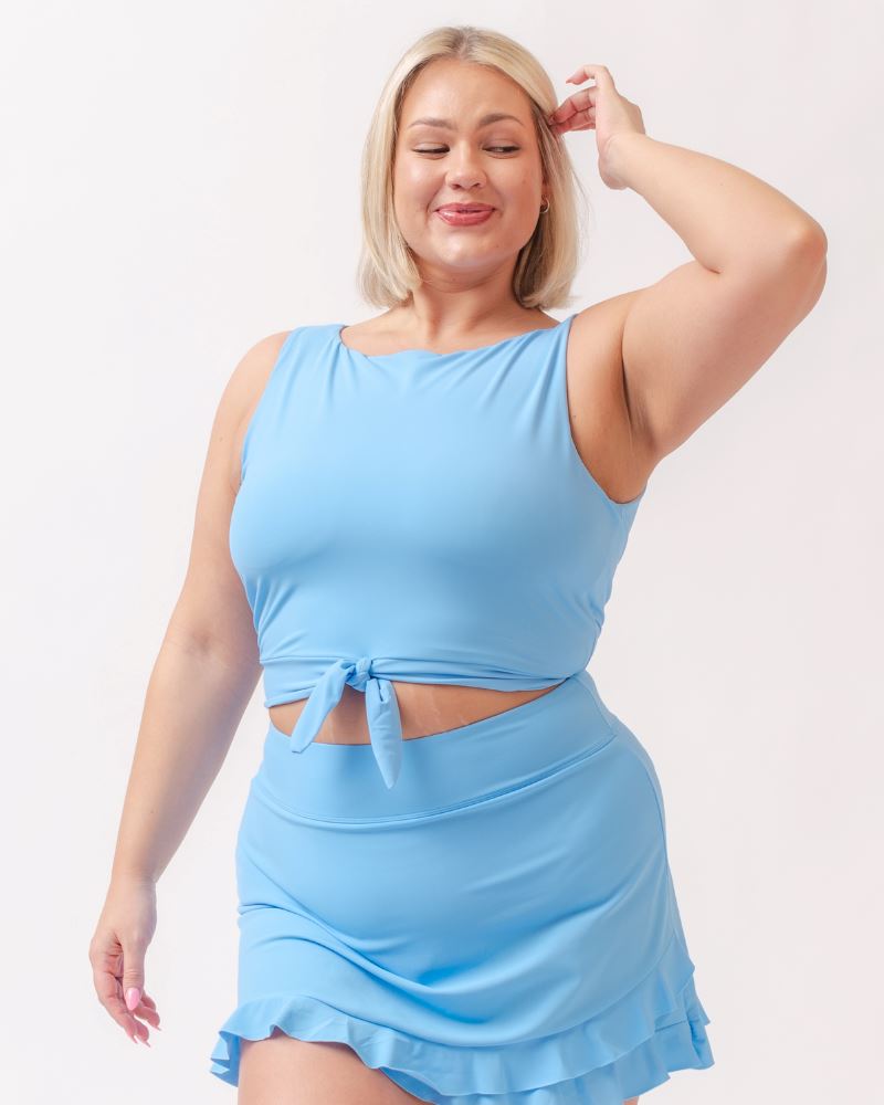 Photo of a woman wearing a light periwinkle blue cropped swim top with a light periwinkle blue swim skirt