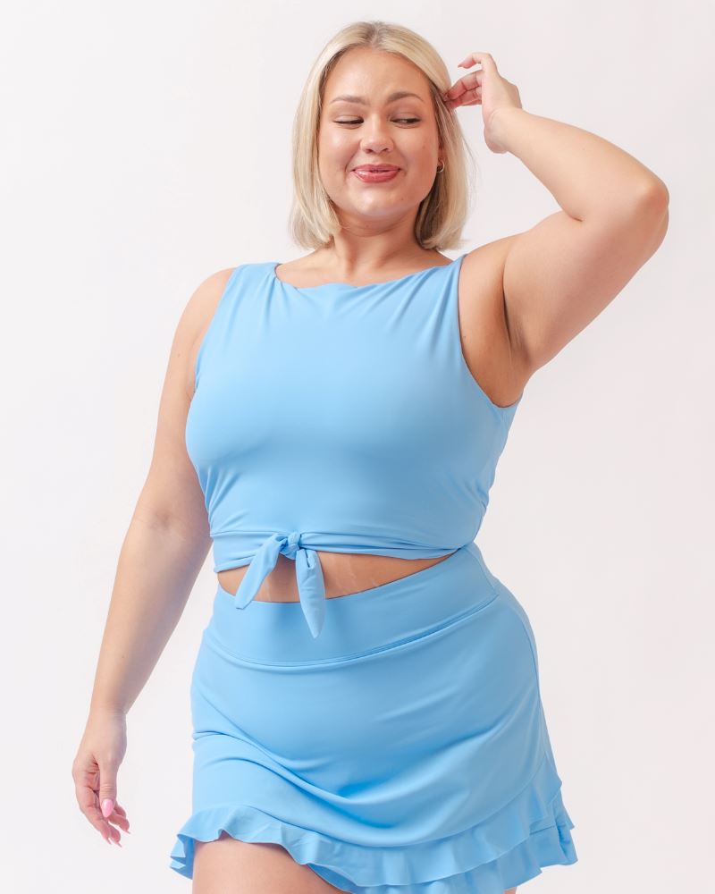 Photo of a woman wearing a light periwinkle blue knotted swim crop top and a light periwinkle blue swim skirt