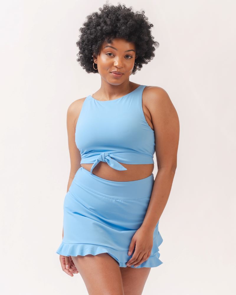 Photo of a woman wearing a light periwinkle blue cropped swim top with a light periwinkle blue swim skirt