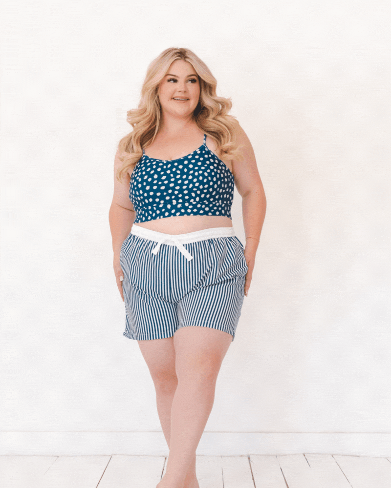 GIF of a woman wearing blue and white stripe swim board shorts and a blue and white dotted swim bralette