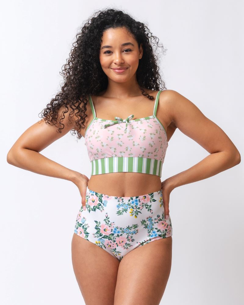Photo of a woman wearing a pink and green floral swim bralette and a white and pink floral/ green striped reversible swim bottom- floral side
