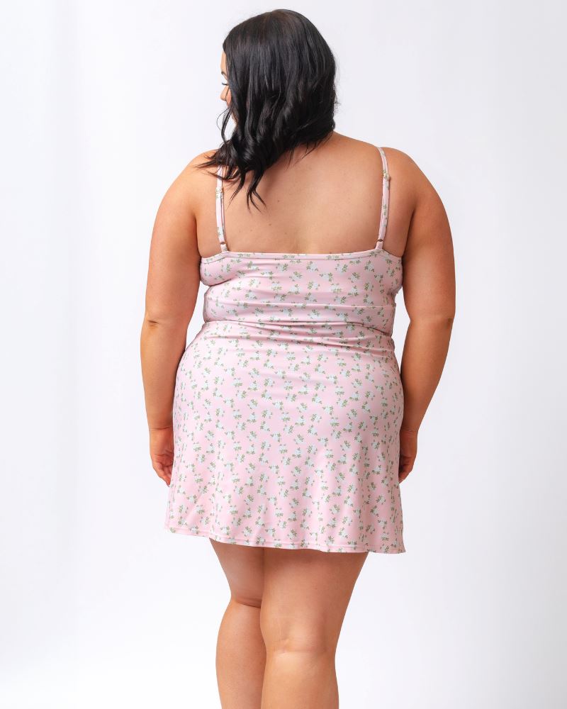 Photo of a woman wearing a pink floral swim dress- back angle