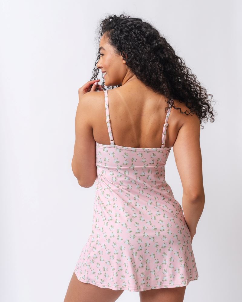 Photo of a woman wearing a pink floral swim dress- back angle