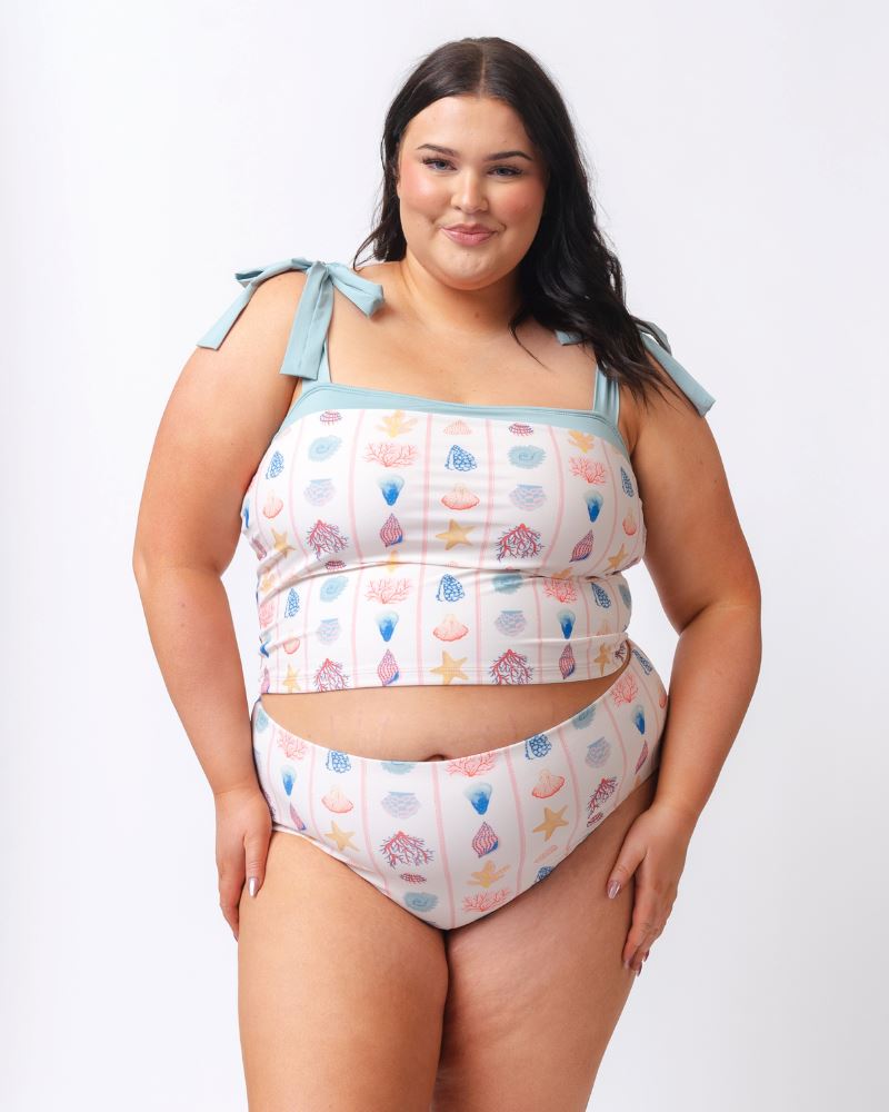 Photo of a woman wearing a seashell striped high waist swim bottom and a seashell striped shoulder-tie swim crop