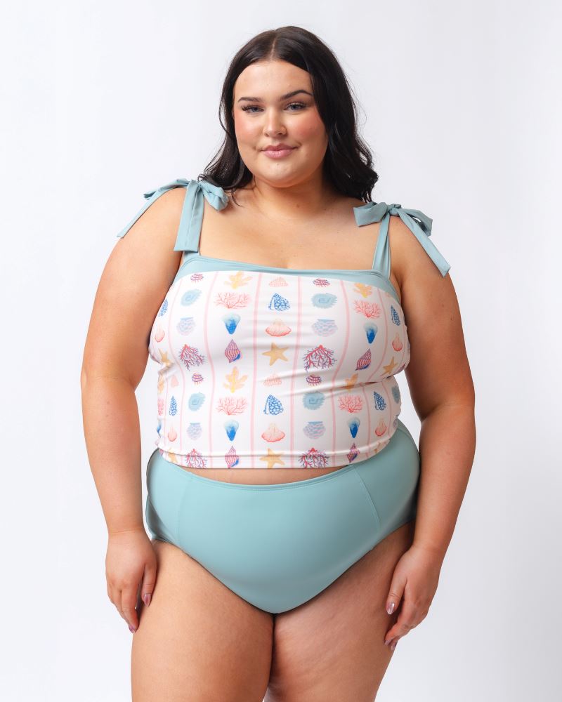 Photo of a woman wearing a seashell striped shoulder-tie swim crop top and a light blue high waist swim bottom
