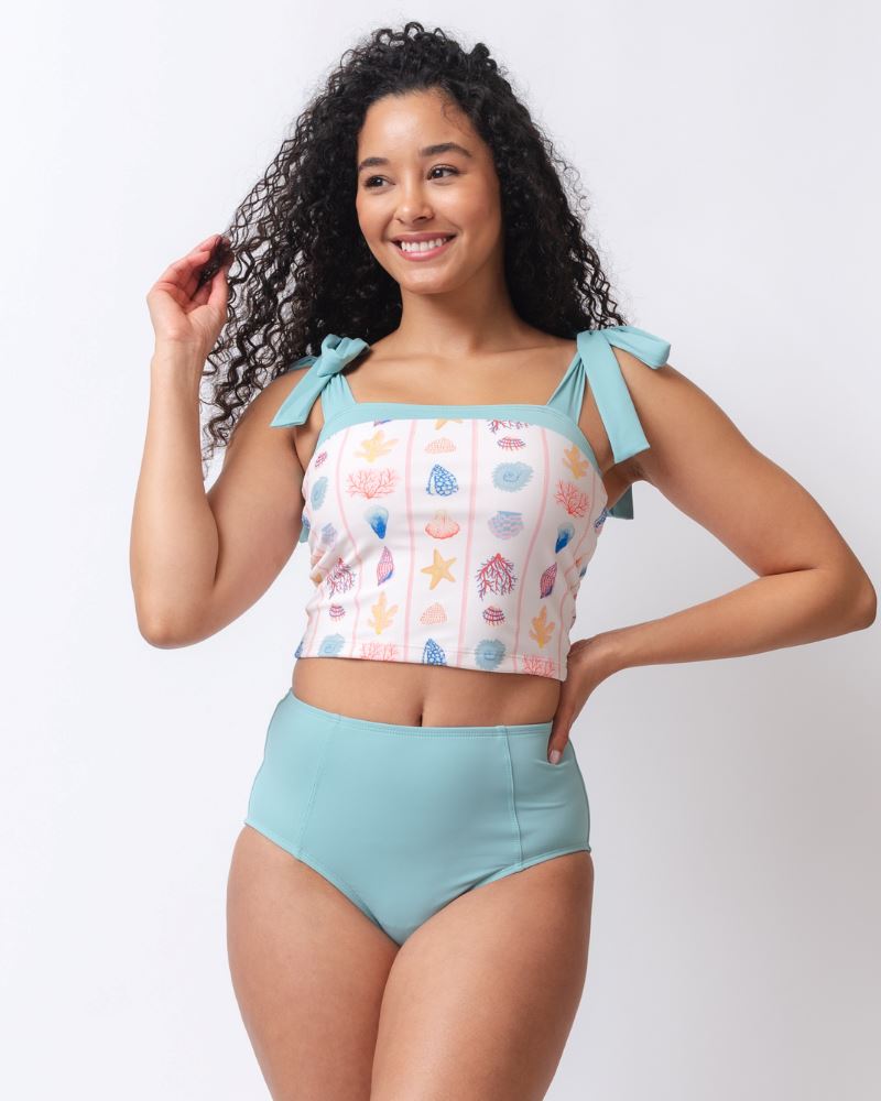 Photo of a woman wearing a seashell striped shoulder-tie swim crop top and a light blue high waist swim bottom