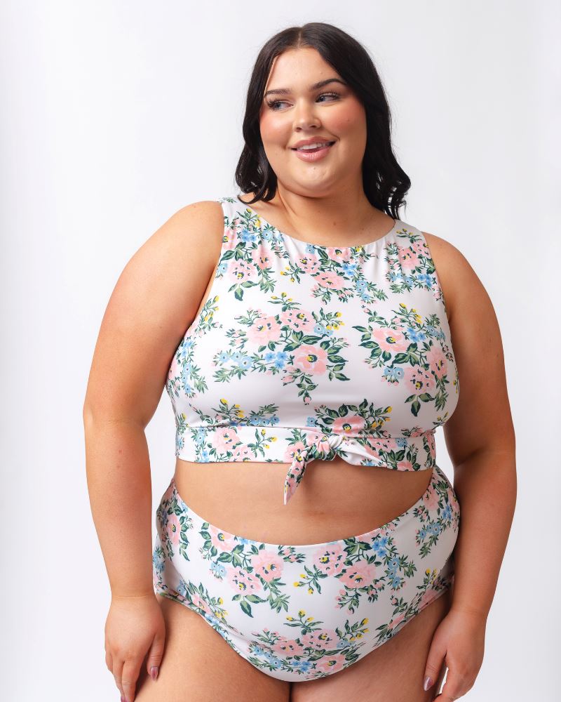 Photo of a woman wearing a pink and white floral cropped swim top with pink and white floral high waist swim bottoms