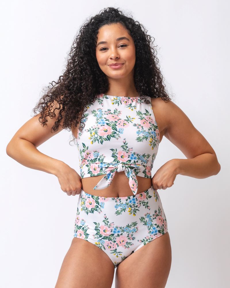 Photo of a woman wearing a pink and white floral cropped swim top with pink and white floral high waist swim bottoms