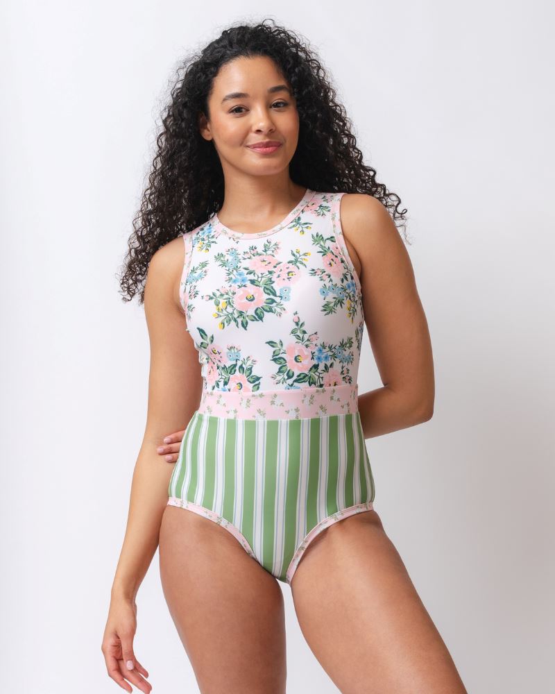 Photo of a woman wearing a pink and white floral with green and white stripes one piece swimsuit