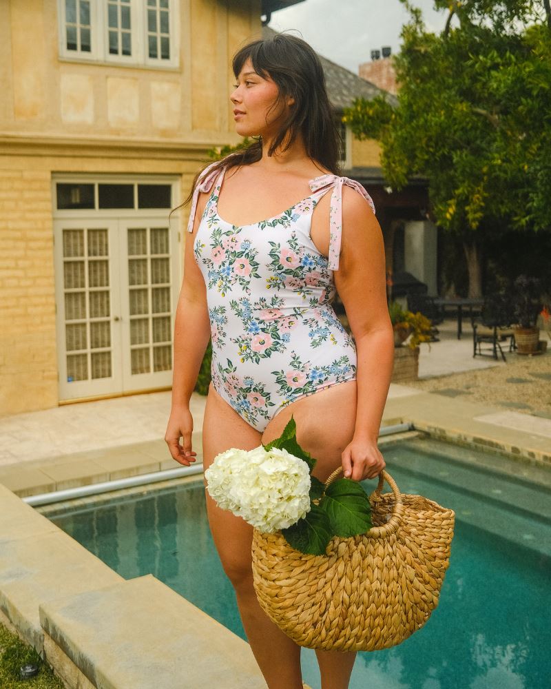 Photo of a woman wearing a pink and white floral one piece swimsuit