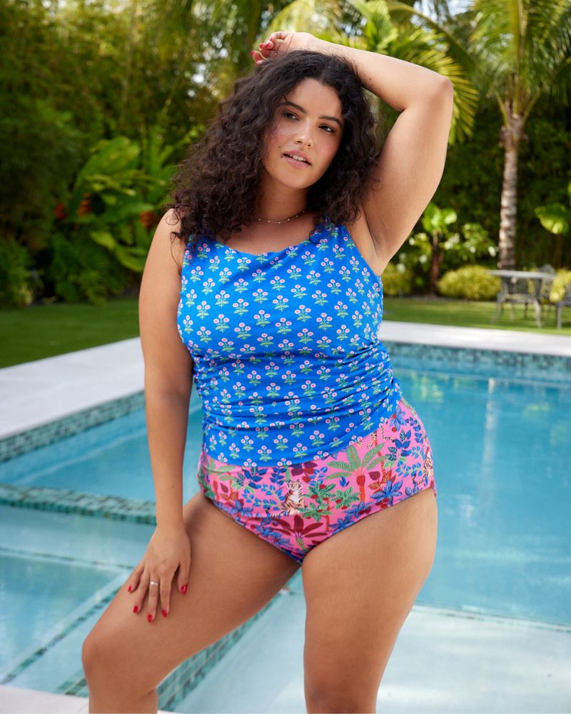 Photo of a woman wearing a bold pink print featuring tigers/ blue and pink floral reversible ultra high waist swim bottoms- tiger side and a blue floral swim tankini top