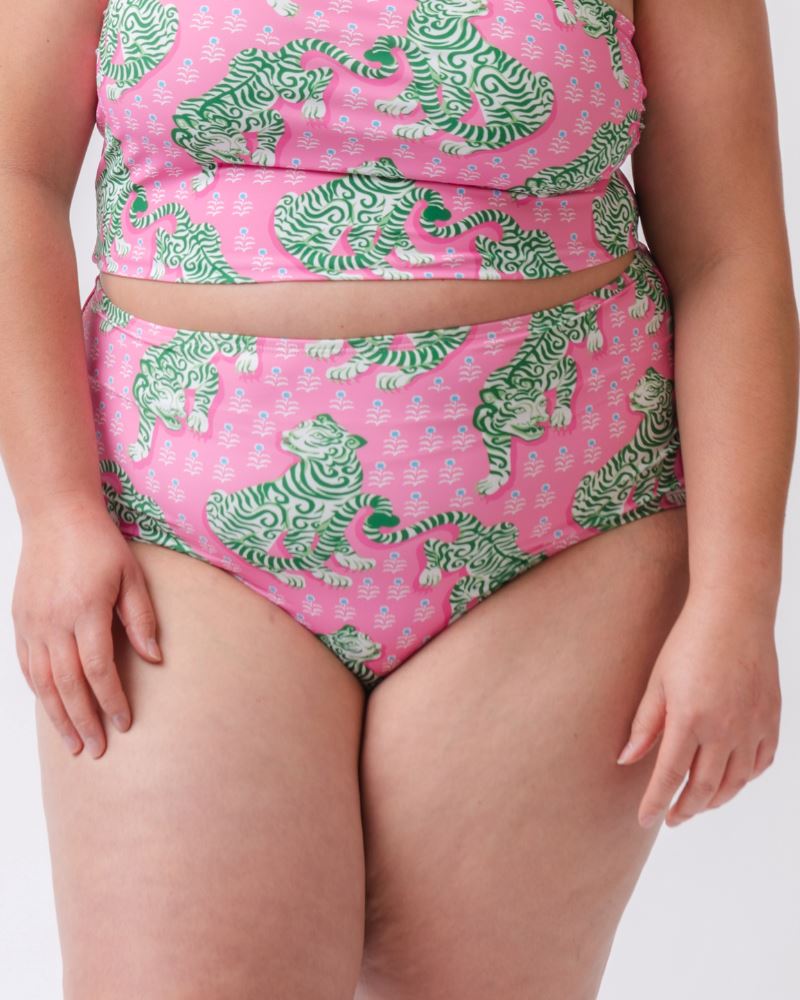 Close up photo of a woman wearing a bold pink and green tiger print high waist swim bottom