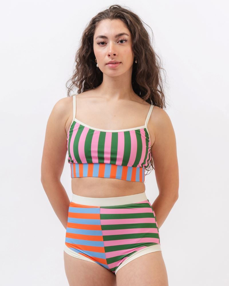 Photo of a woman wearing a multi-colored striped retro swim short bottom and a multi-colored striped swim bralette