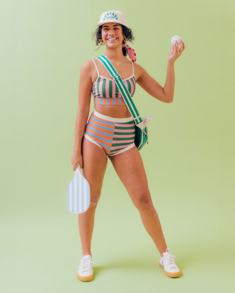 Photo of a woman wearing a multi-colored striped swim bralette and a multi-colored striped retro swim short bottom