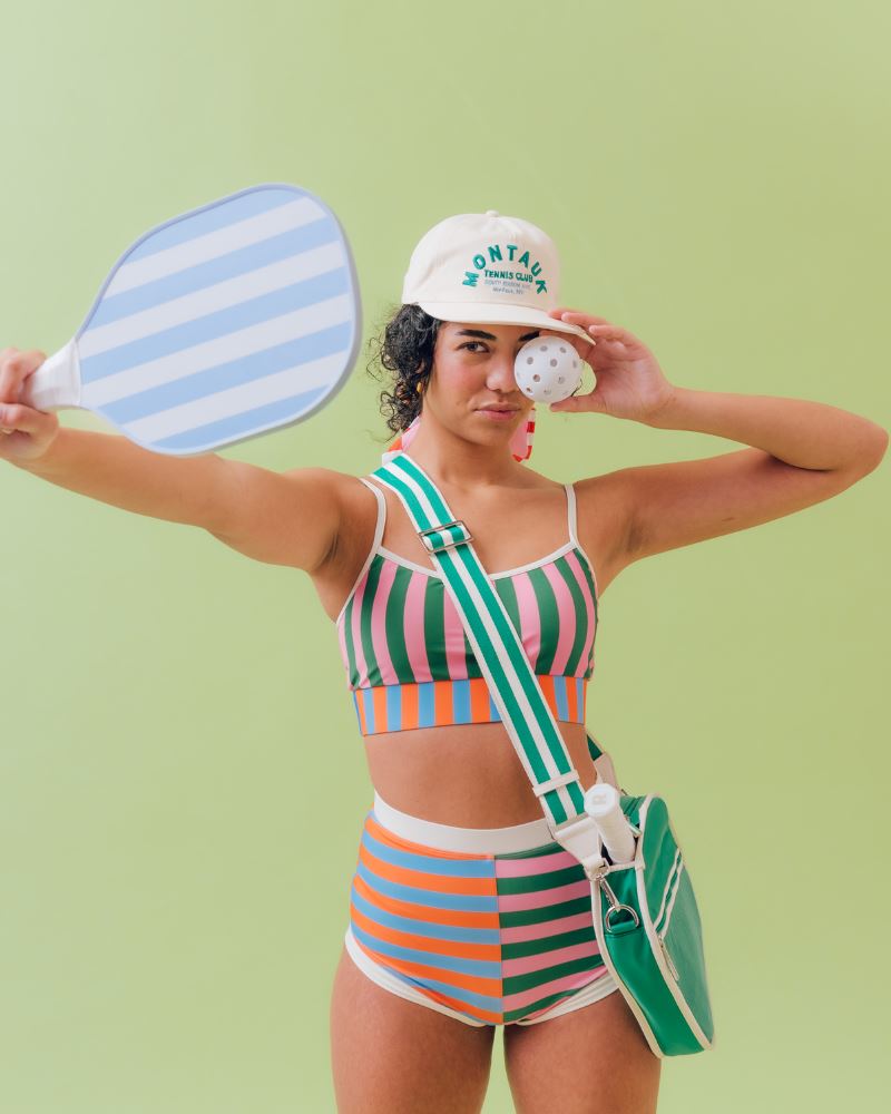 Photo of a woman wearing a multi-colored striped swim bralette and a multi-colored striped retro swim short bottom