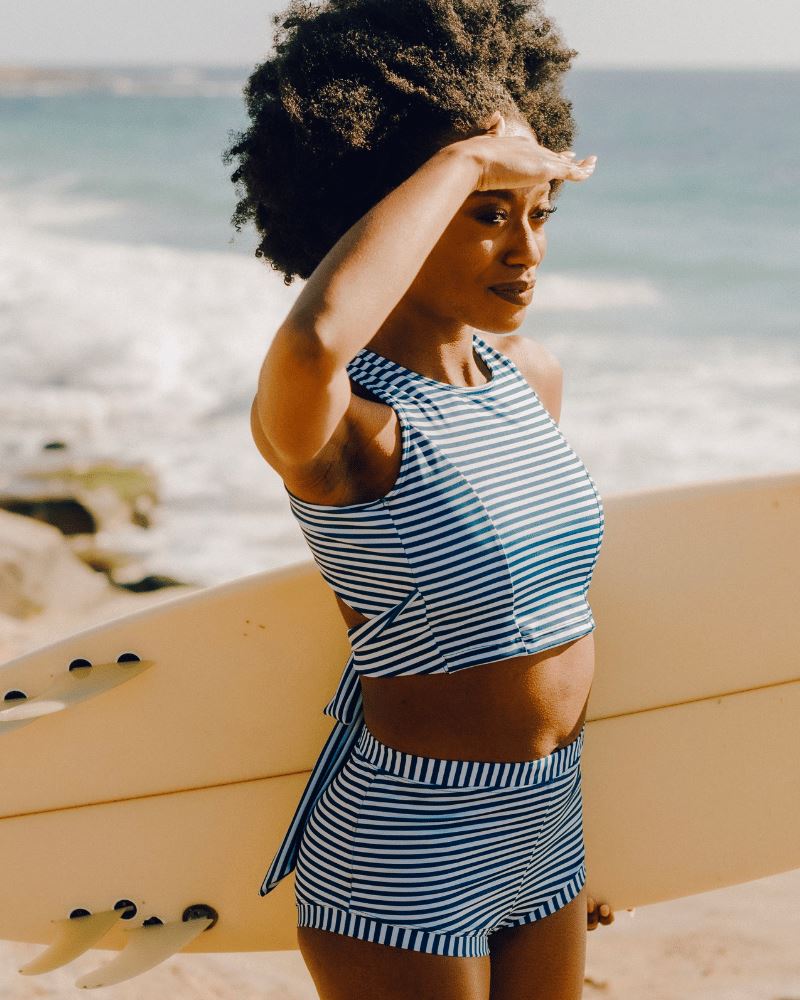 Photo of a woman wearing an Indigo stripe cross-back swim crop top and an Indigo stripe swim short bottom side angle