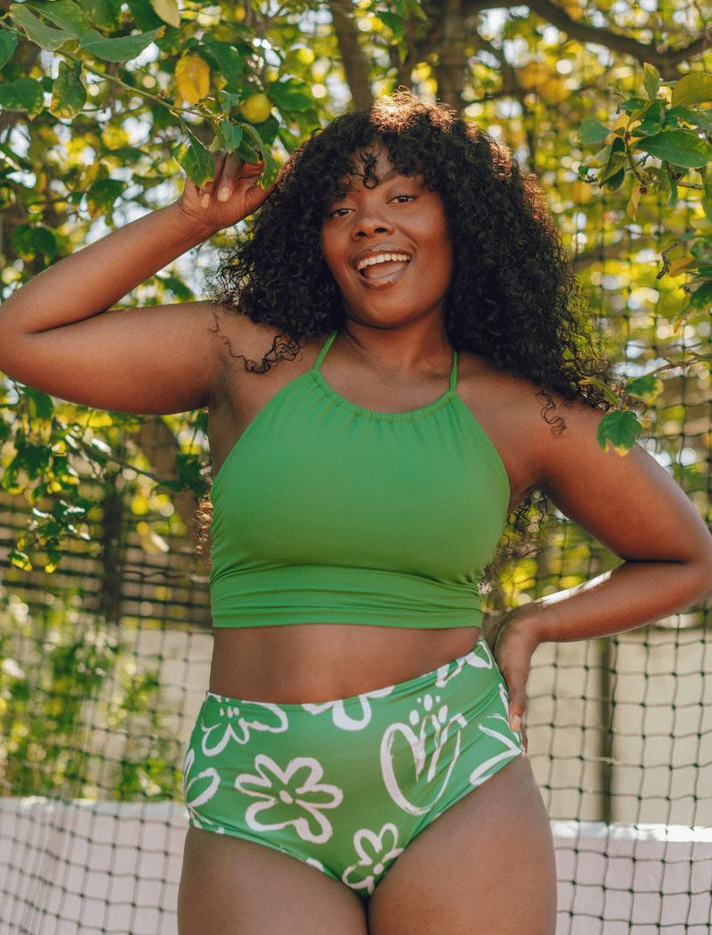 Photo of woman wearing green cropped lace back swim top with green and white floral swim bottoms