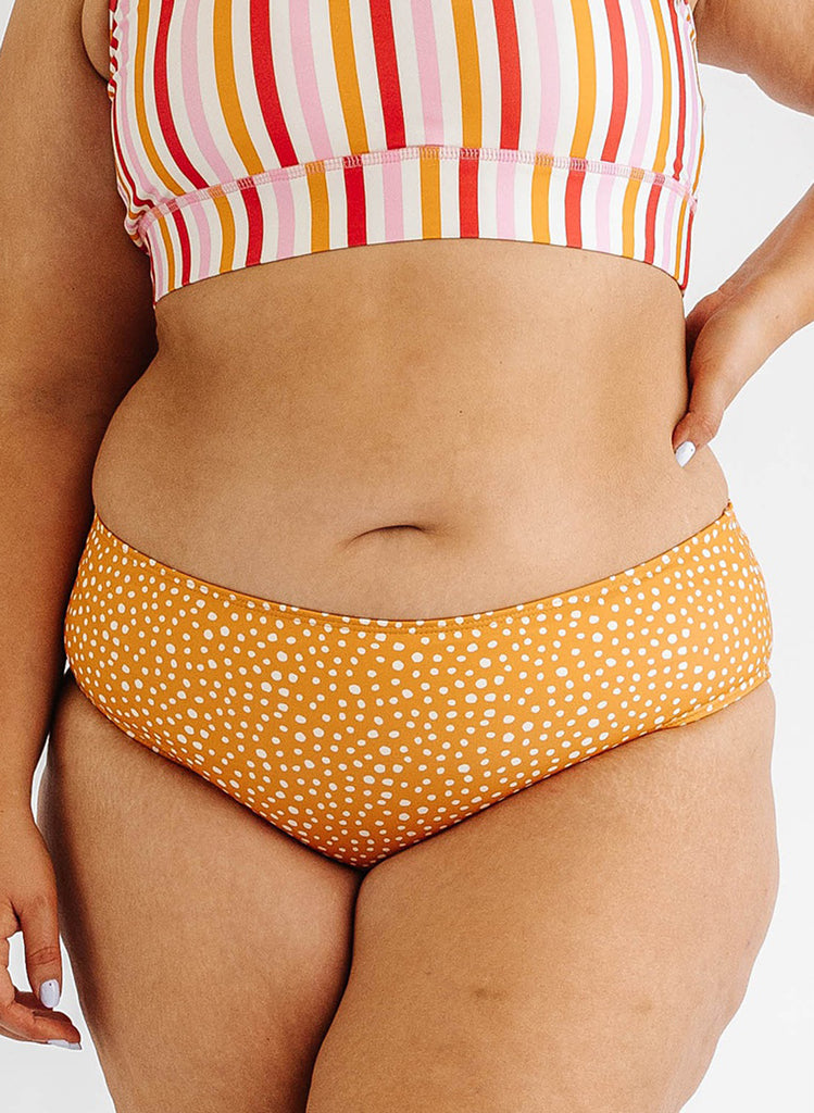 Photo of woman wearing orange and white dot mid waist swim bottoms