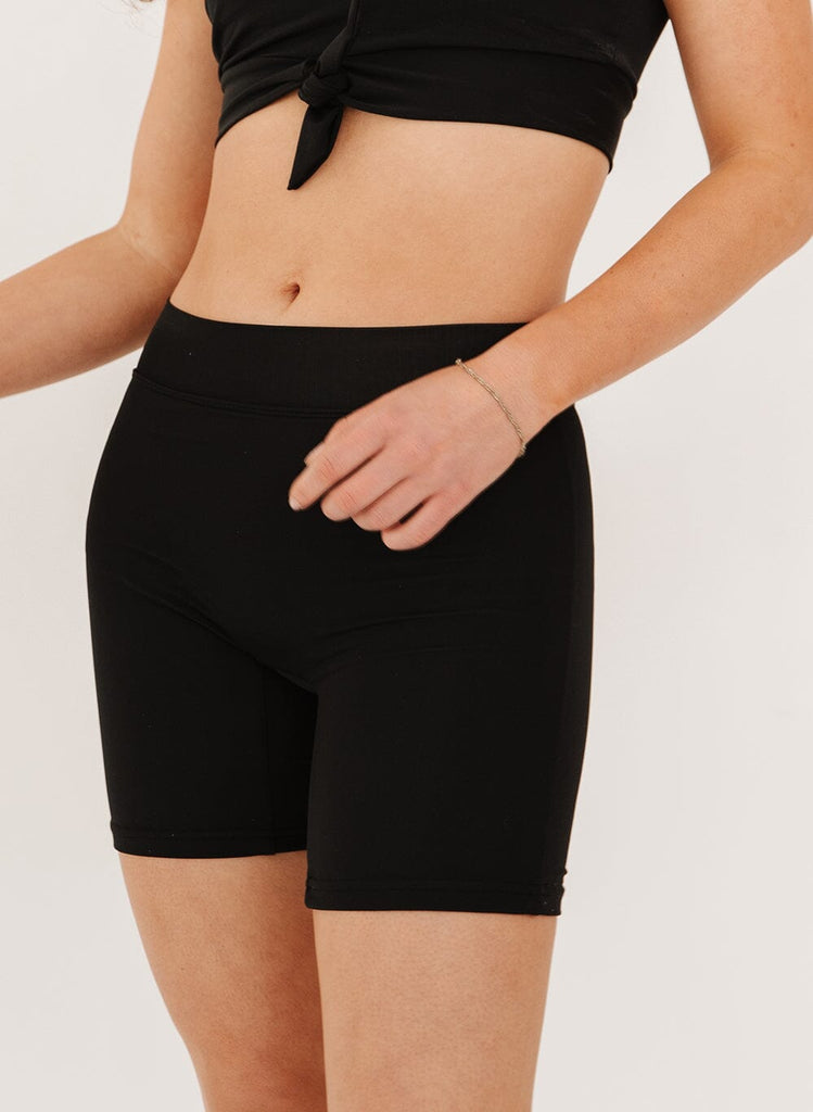 Photo of a woman wearing black mid thigh shorts.