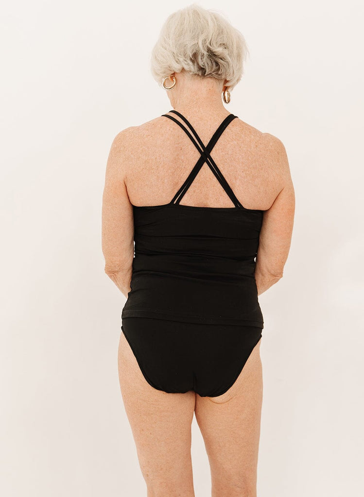 Photo of a woman wearing a black double cinch swim tankini top and black swim bottoms back angle