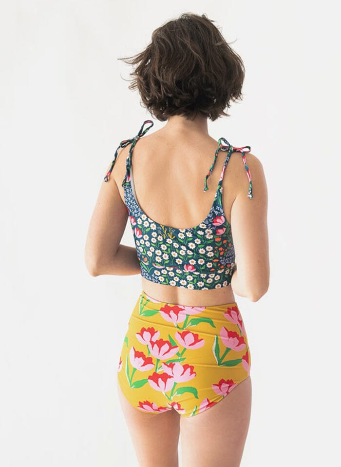 Photo of a woman wearing a Claus/Tage reversible swim bottom Claus side and a Blixen shoulder-tie swim crop top back angle