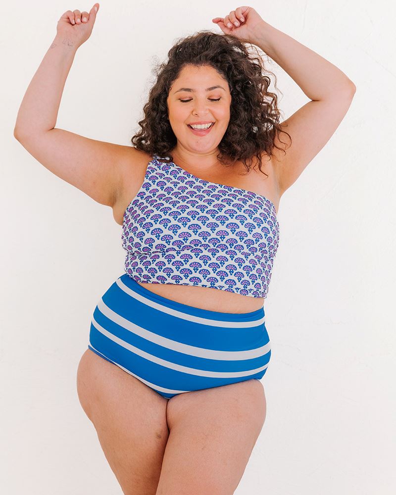Photo of a woman wearing a Block Floral One-shoulder swim crop top and a blue and white stripe swim bottom