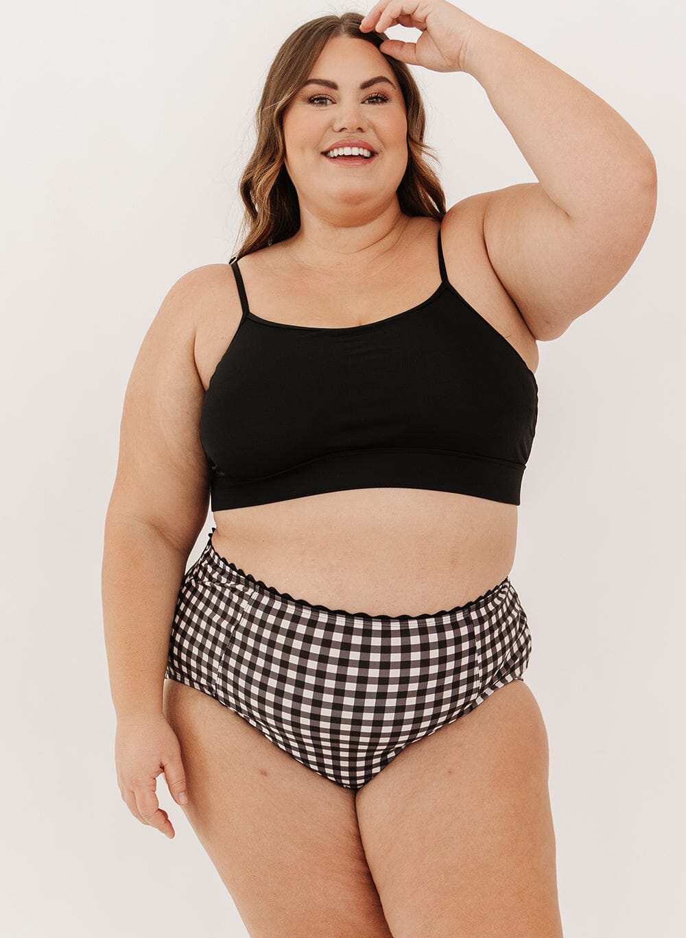 Woman wearing a black swim bralette and black gingham swim bottoms