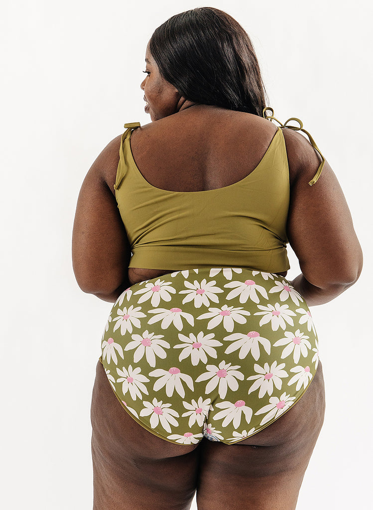 Photo of woman wearing green cropped swim top with green and white floral swim bottoms back angle