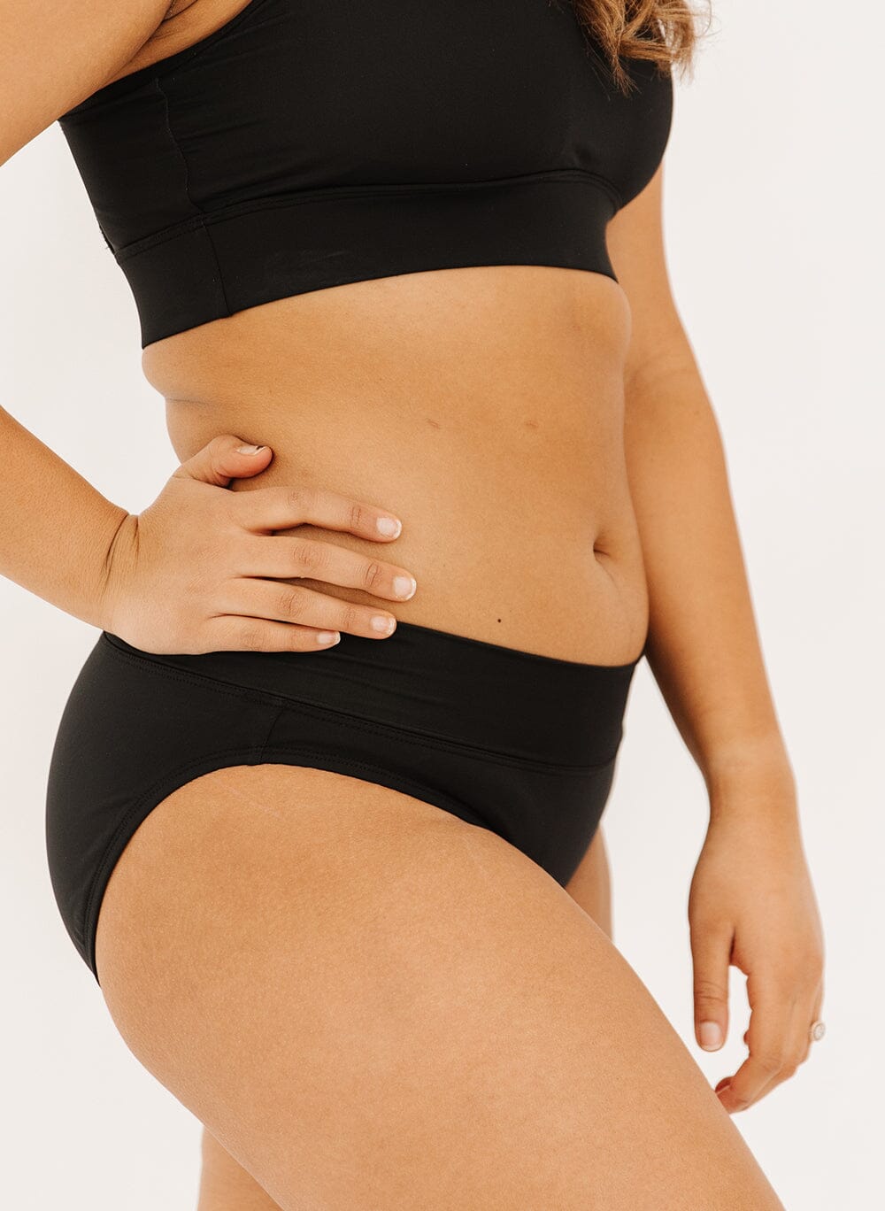 Photo of a woman in black classic swim bottoms side angle