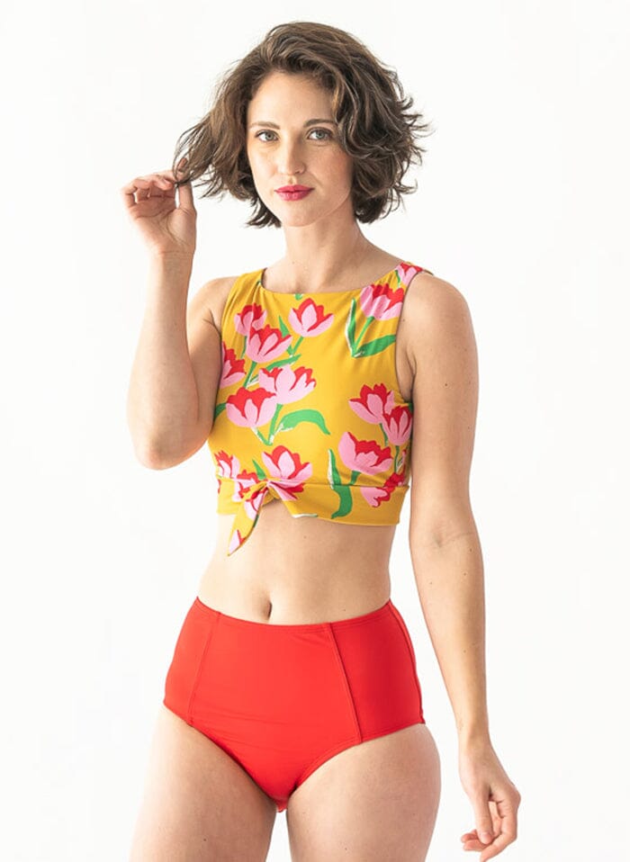 Photo of a woman wearing a red swim bottom and a yellow floral swim crop top
