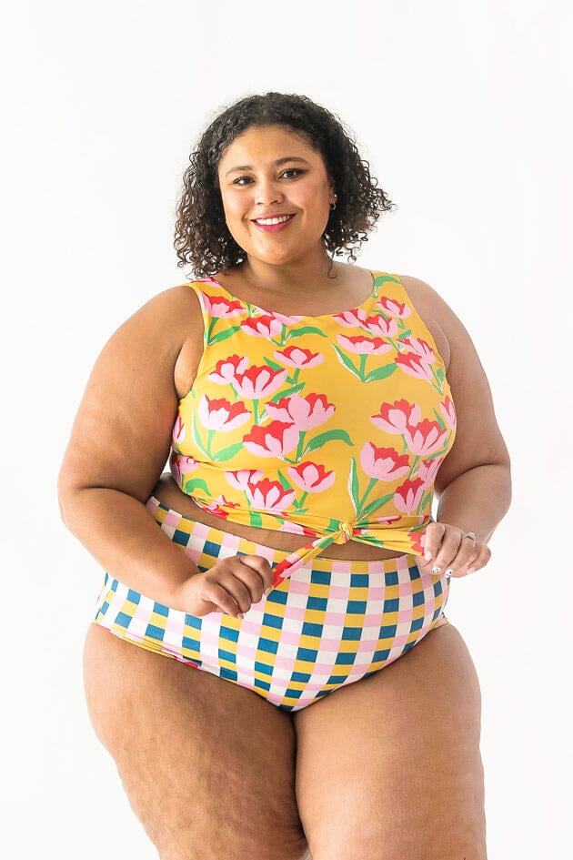 Photo of a woman wearing a Claus swim crop top and a multi color checkered swim bottom