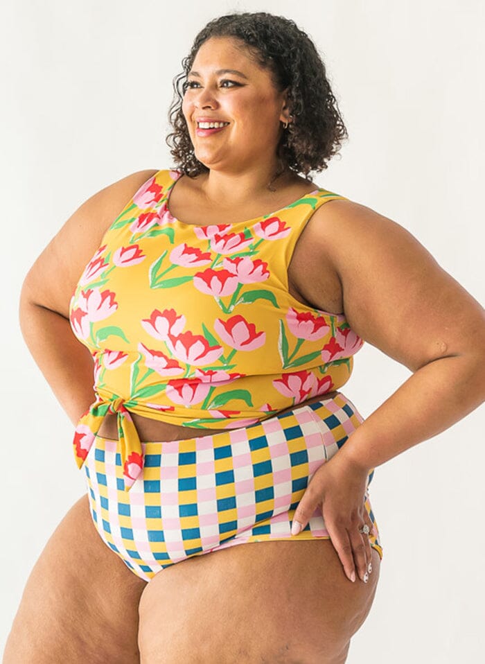 Photo of a woman wearing a Claus/Tage reversible swim bottom checkered side and a Claus swim crop top side view
