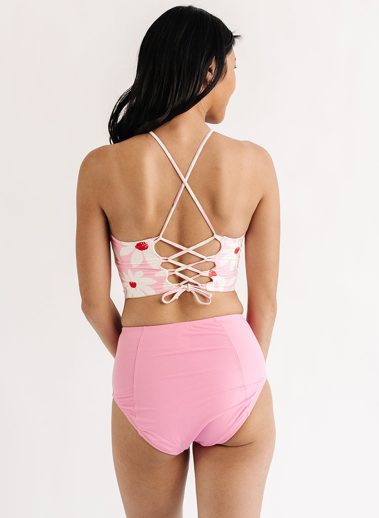 Photo of woman wearing pink floral lace back swim top with pink swim bottoms back angle