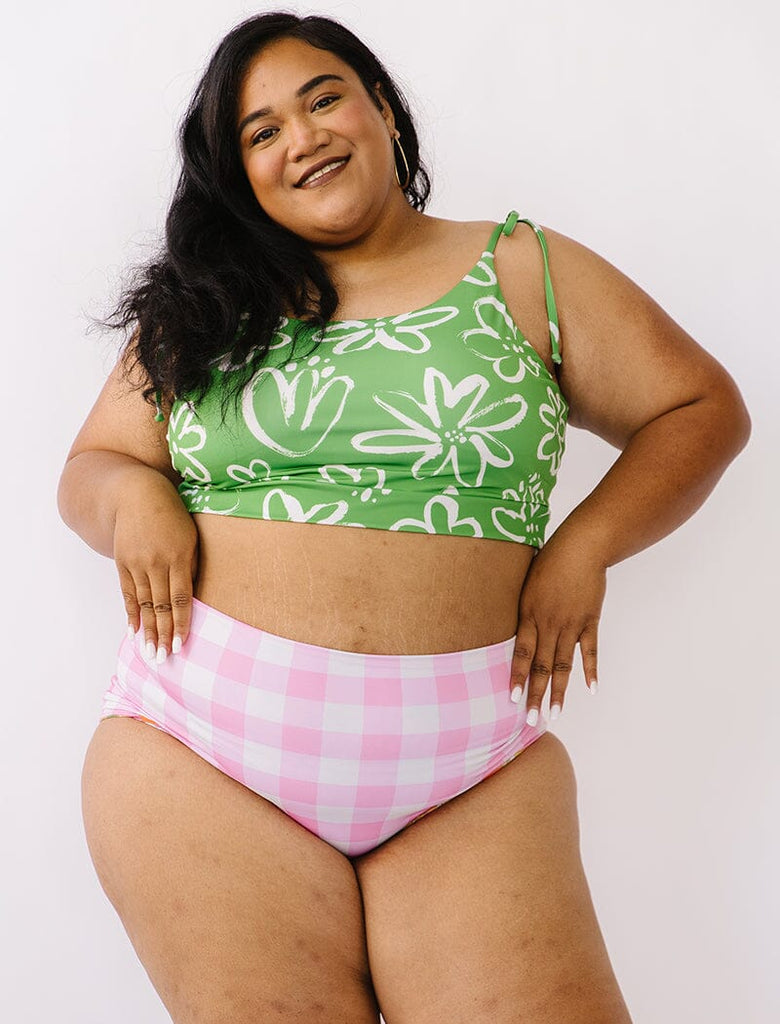 Photo of woman wearing green and white floral cropped swim top with pink gingham swim bottoms