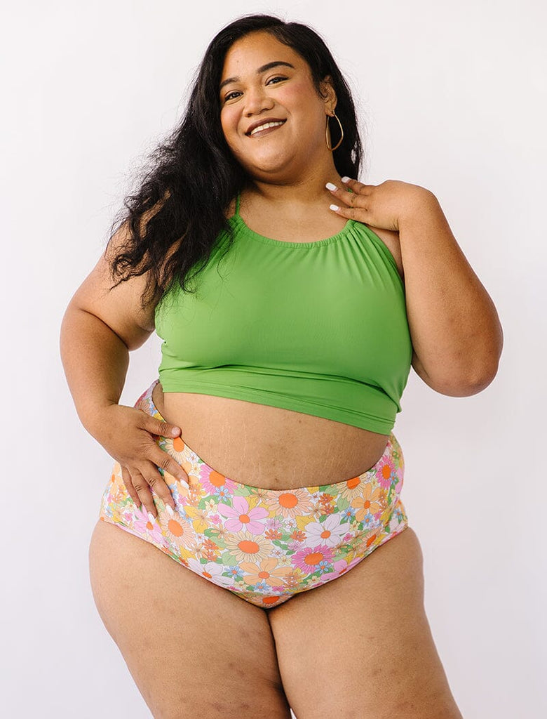 Photo of woman wearing green lace back cropped swim top with multi colored floral  swim bottoms
