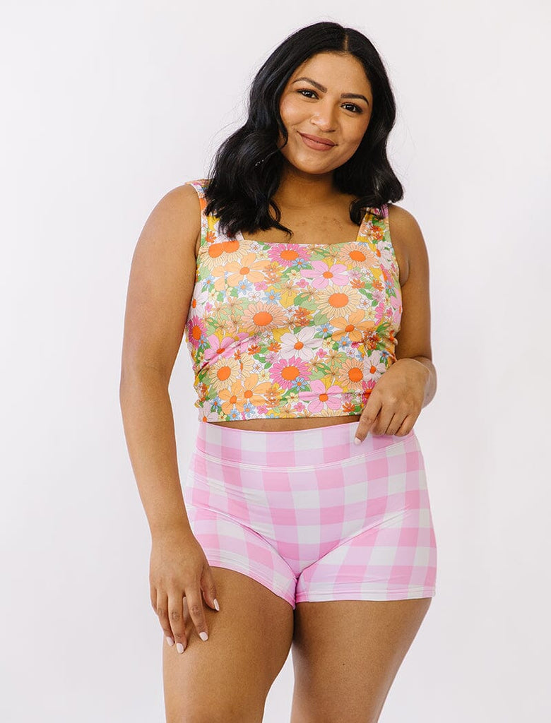 Photo of woman wearing multi colored floral square neck swim top with pink gingham swim shorts