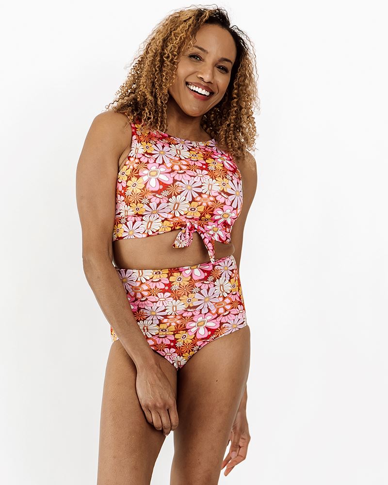 Photo of a woman wearing a Groovy Blooms floral knotted swim crop top and a Groovy Blooms floral swim bottom