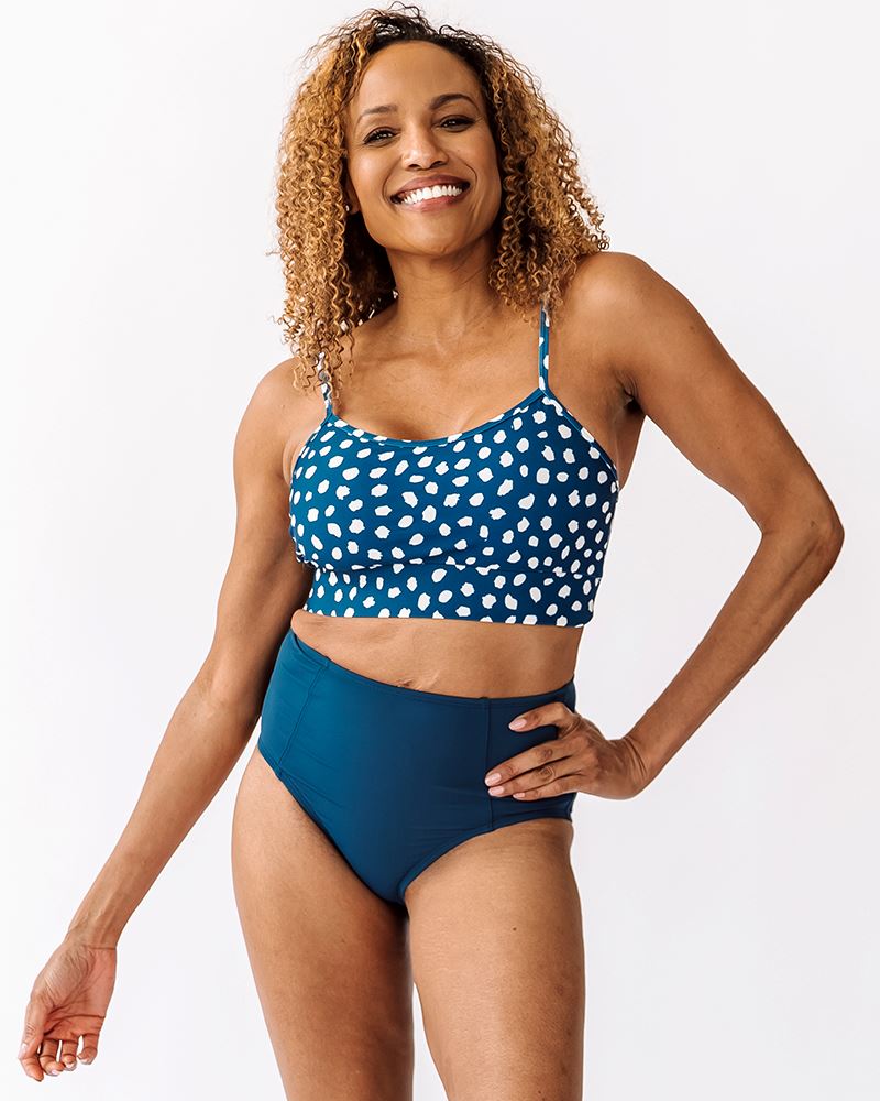 Photo of woman wearing blue and white dot bralette swim top with blue high waisted swim bottoms