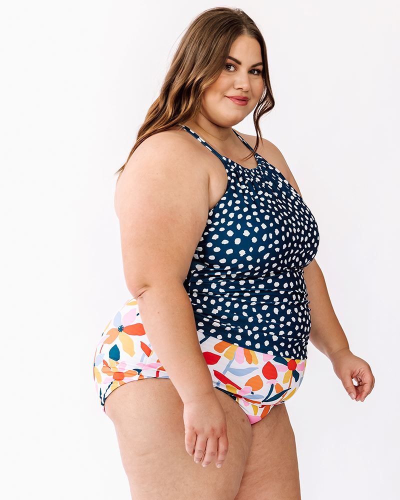 Photo of a woman wearing an Indigo dot double-cinch swim top and a multi color floral swim bottom side angle