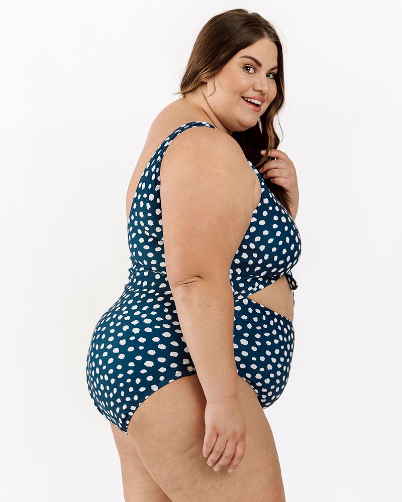 Photo of a woman wearing an Indigo dot knotted one-piece swim suit side angle