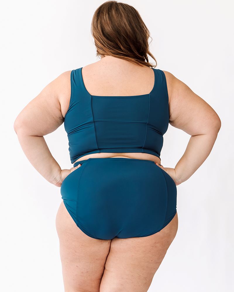 Photo of woman wearing blue square neck cropped swim top with blue high waisted swim bottoms back angle