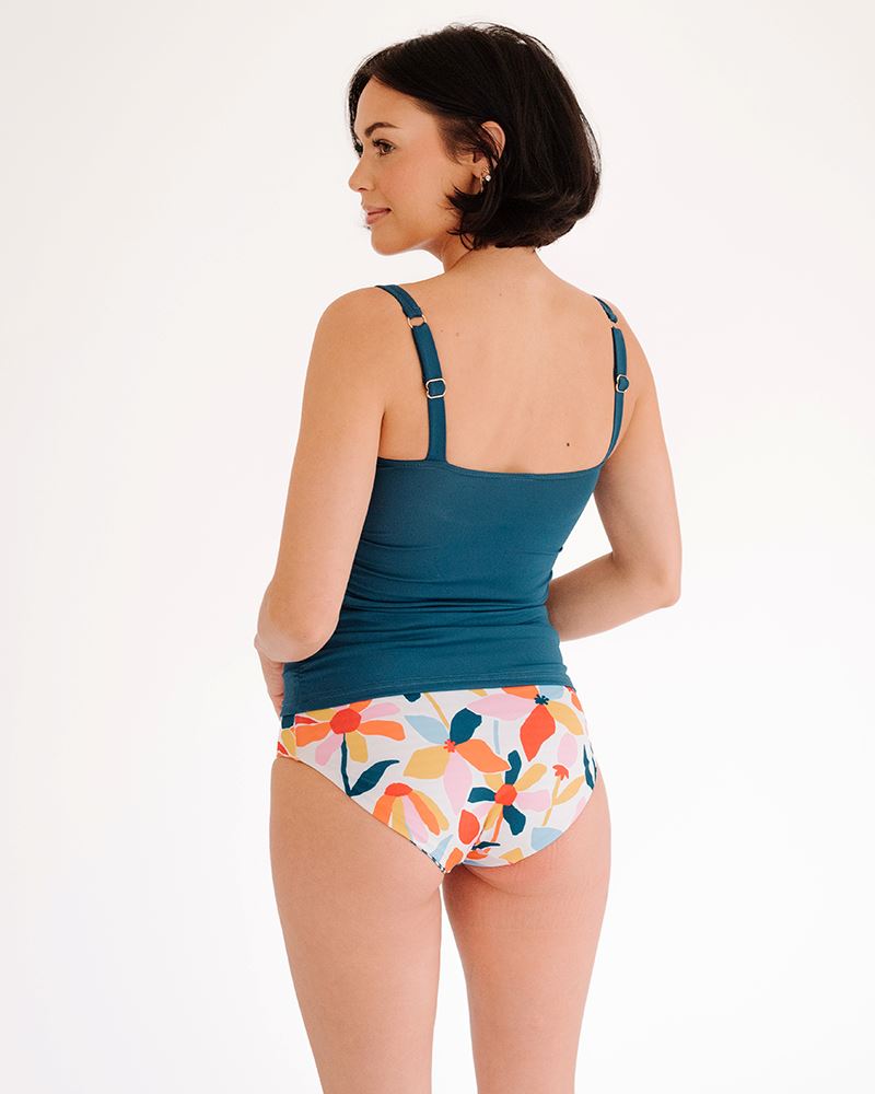 Photo of a woman wearing an Indigo square neck swim top and a multi color floral swim bottom back angle