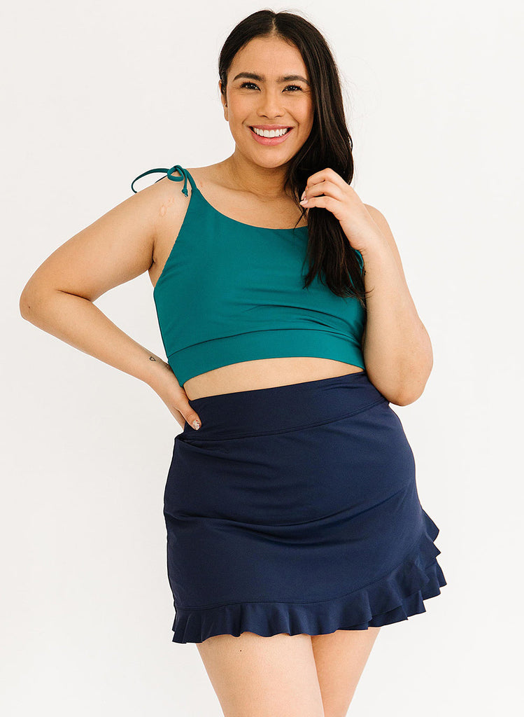 Photo of a woman wearing a blue cropped swim top with a blue swim skirt