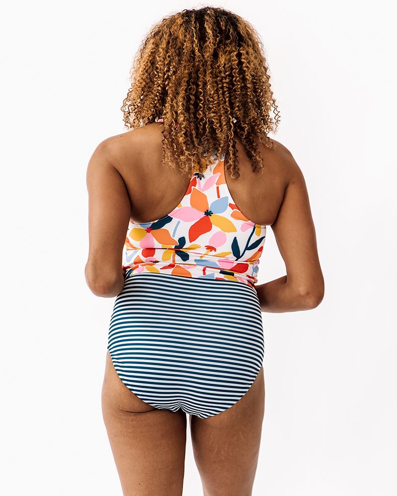 Photo of a woman wearing a June floral/ Indigo stripe reversible swim bottom stripe side and a June floral swim crop top back angle