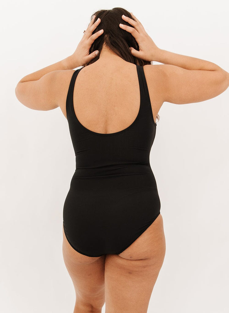 Photo of a woman wearing a black knotted one-piece swim suit back angle