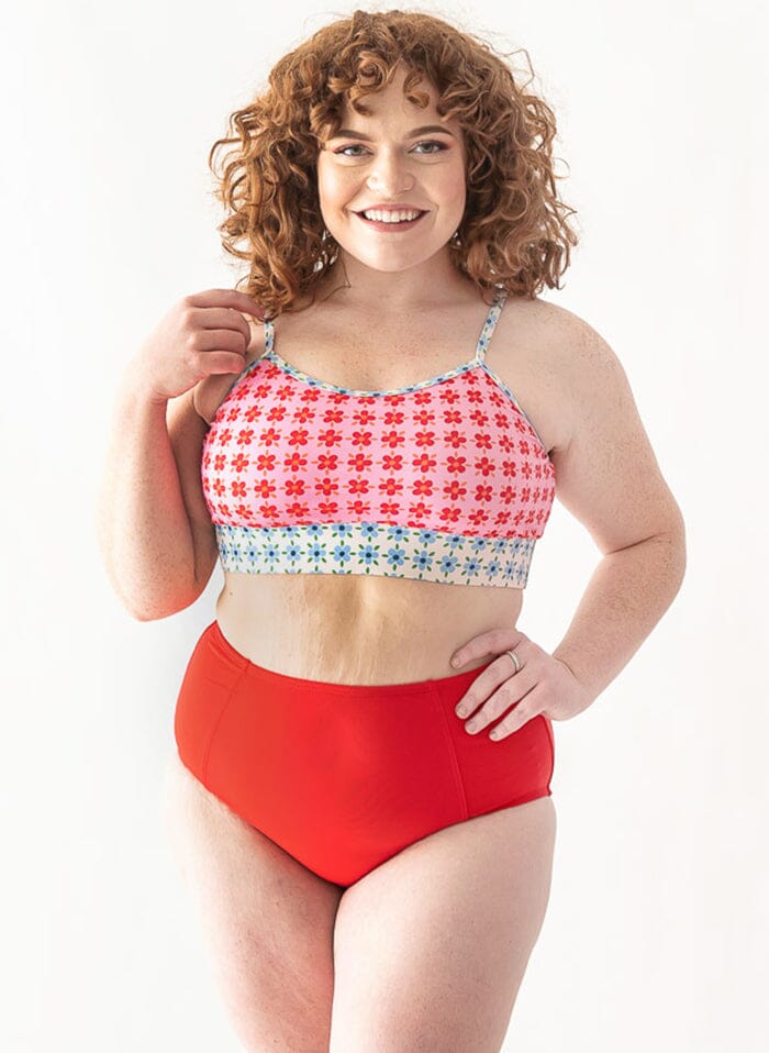 Photo of a woman wearing a red swim bottom and a floral swim bralette